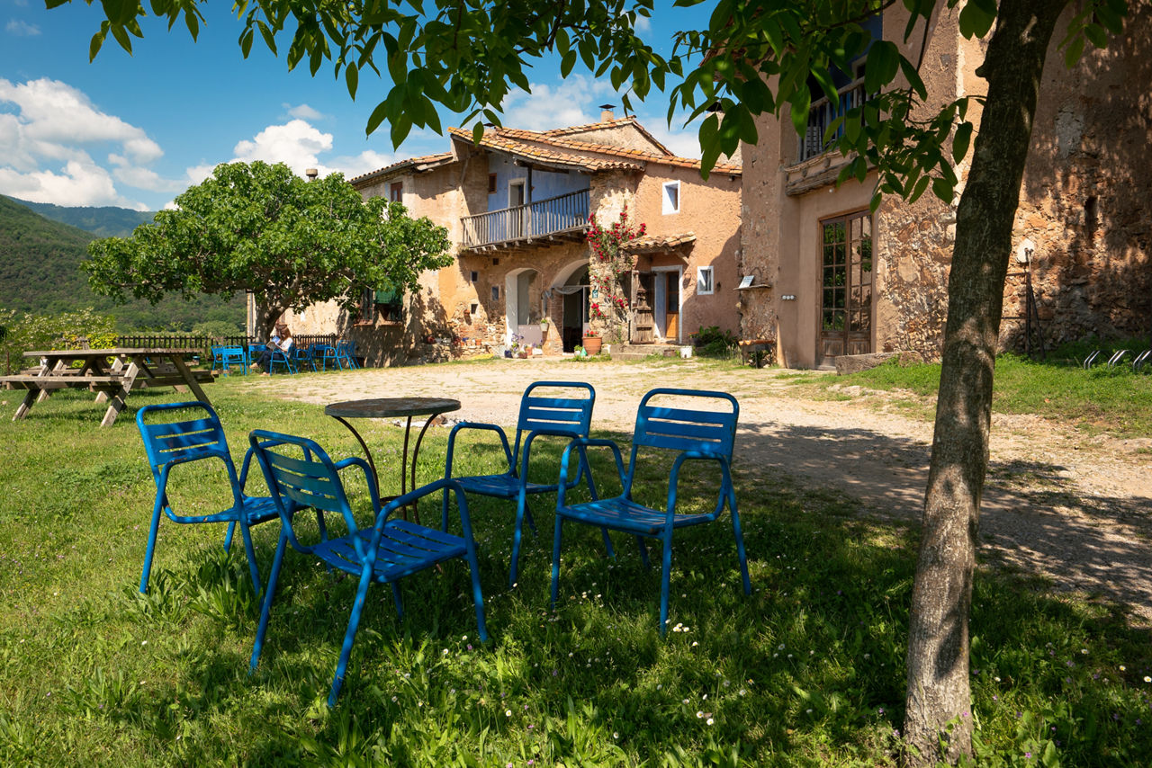 Taules i cadires a l'exterior de la Masia Mas Garganta ubicada a la Vall d'en Bas.