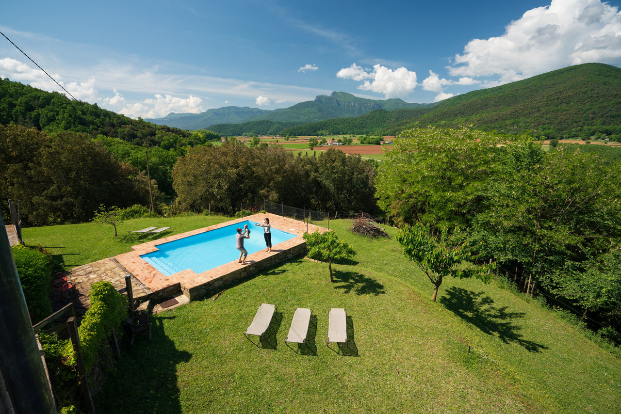 Parella amb un nadó a la piscina exterior de la Masia Mas Garganta ubicada a la Vall d'en Bas.