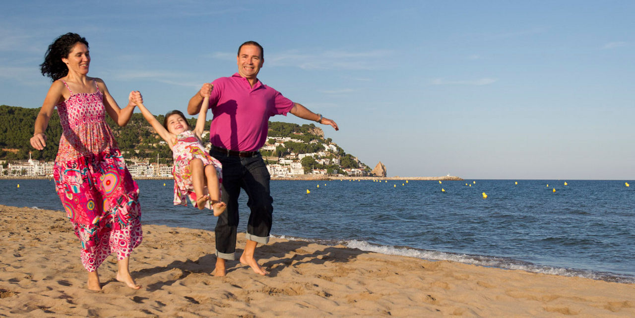 Mare i pare jugant amb la seva filla a la platja de Torroella de Montgrí.