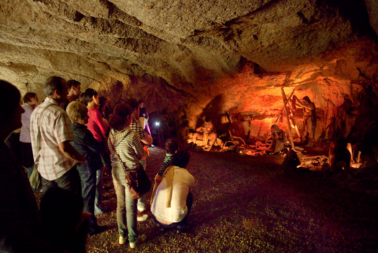 Grup de visitants a les coves de l'Espluga davant d'una de les representacions de la vida prehistòrica.