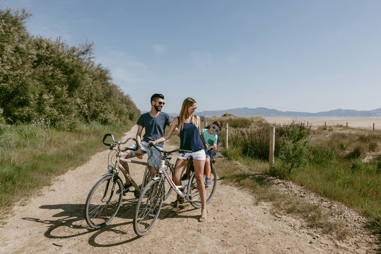Família amb bicicleta per un camí al costat de la platja de Sant Pere Pescador.