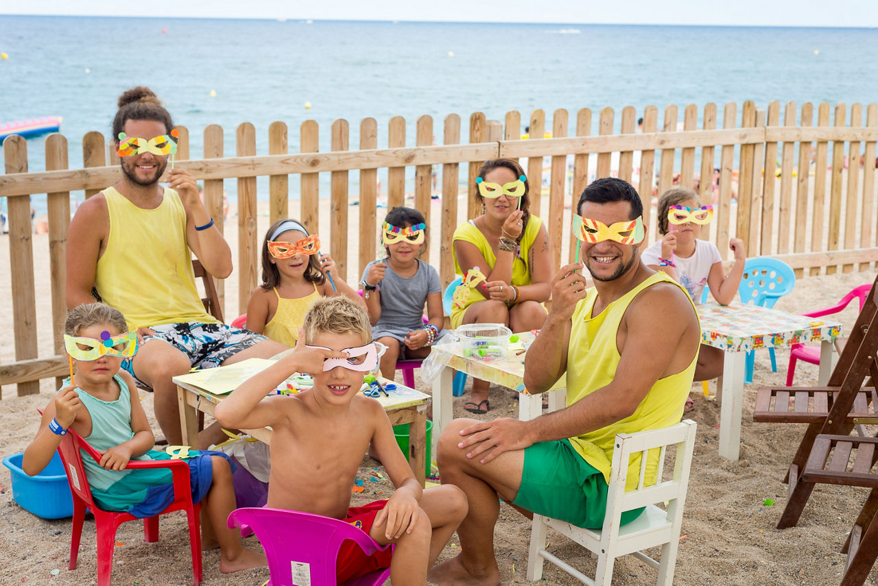 Grup de nens i nenes amb monitors fent propostes lúdico-educatives al Miniclub situat a la Platja Gran de Platja d'Aro.