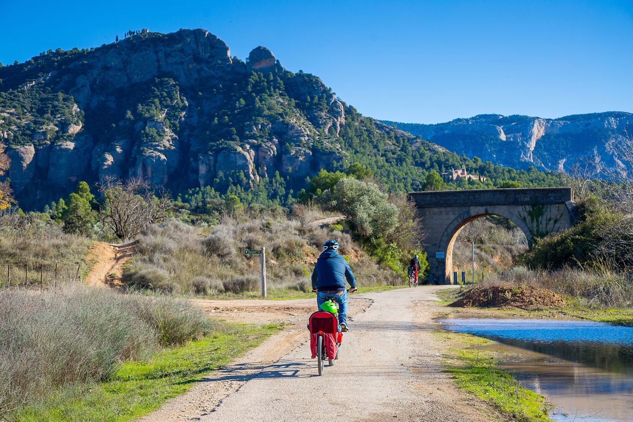 Un pare i el seu fill passegen en bici a la via verda.