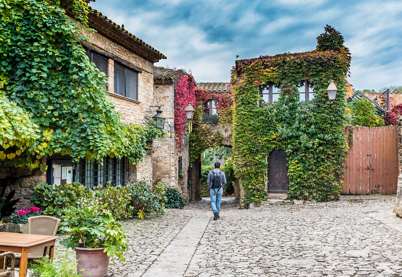 Home caminant d'esquenes pel casc antic de Peratallada.